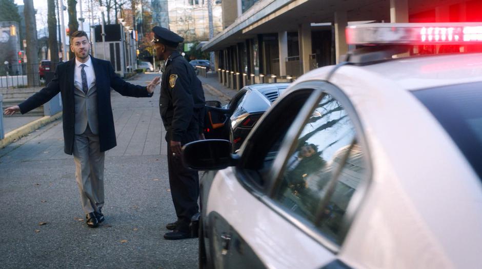 A police officer conducts a sobriety test on the owner of the fancy car.