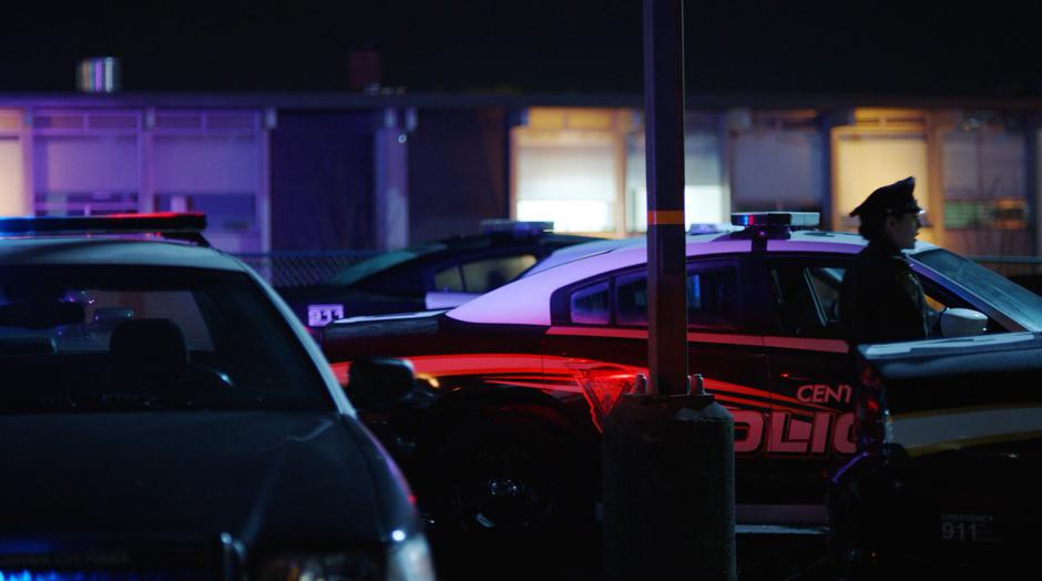 A police officer stops when the siren starts going off on one of the squad cars.