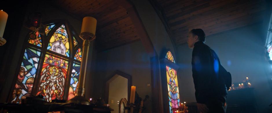 Pike stands in front of the alter examining the stained glass windows.