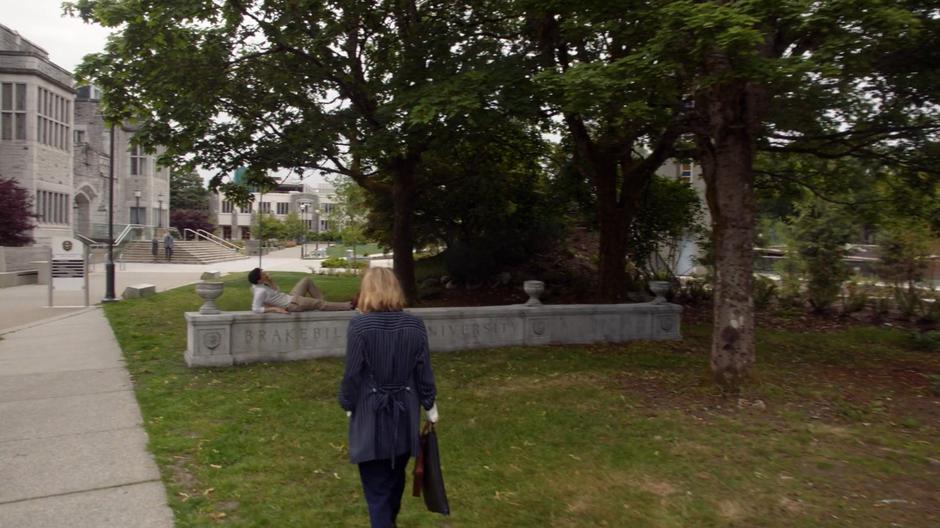 Kimber D'Antoni walks down the path to where Todd is lounging on the university's sign.