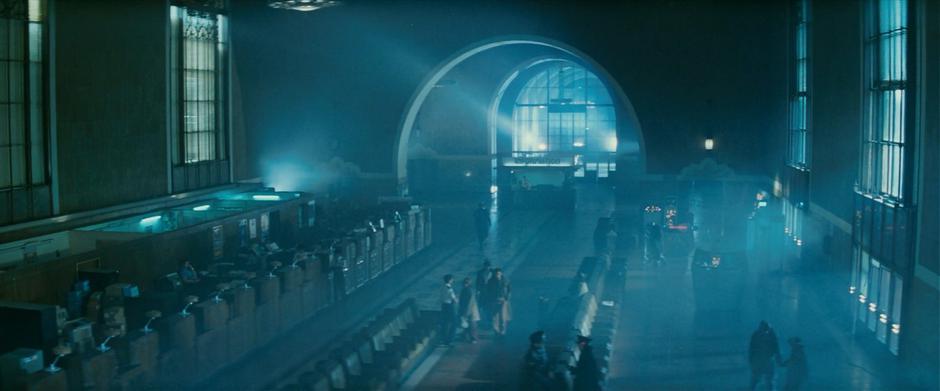 Deckard walks through the police station in front of Gaff.