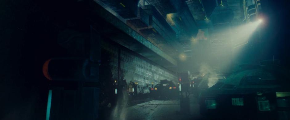 Deckard drives his car up the street next to his apartment building.