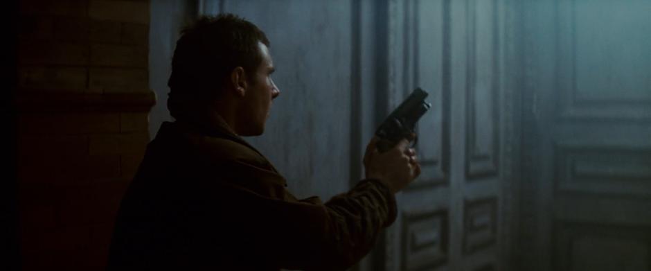 Deckard holds up his gun as he approaches the apartment door.