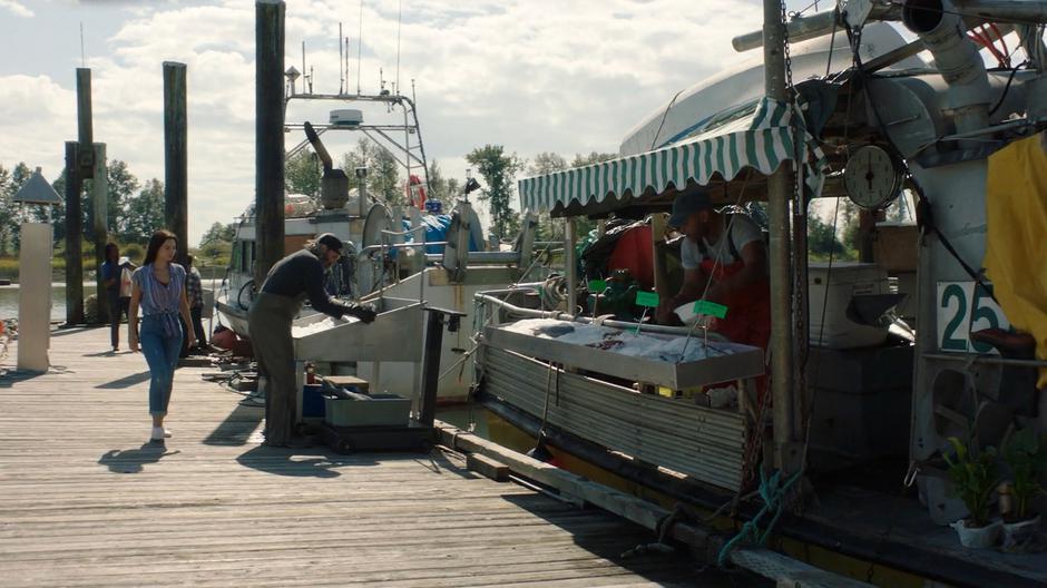 Ryn walks down to dock to a man selling fish from the side of his boat.