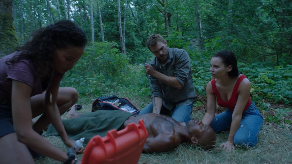 Maddie, Ben, and Ryn kneel down over the injured mermaid.