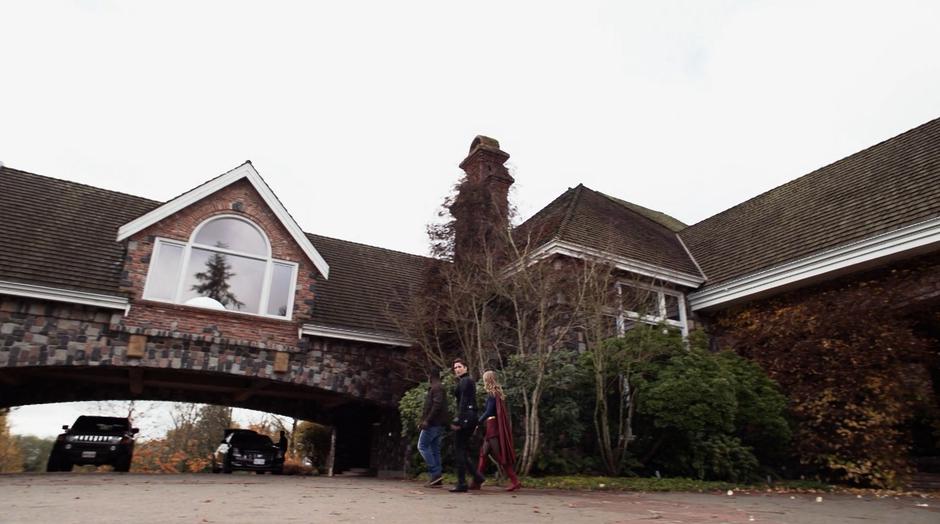 J'onn, Alex, and Kara walk around the corner to where General Tan is loading his car.