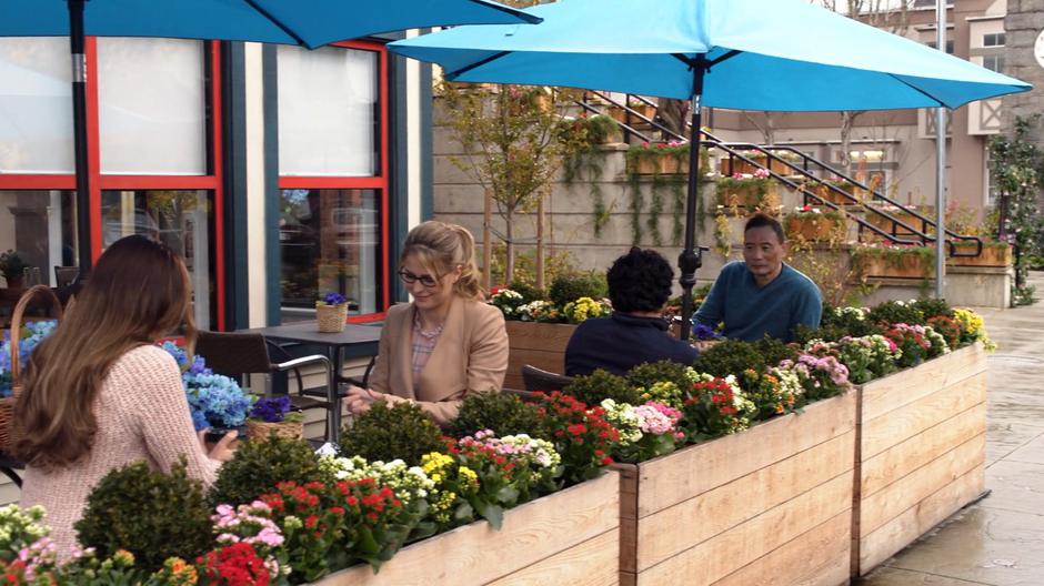 Maeve and Kara settle down in the cafe's outdoor seating over coffee to talk.