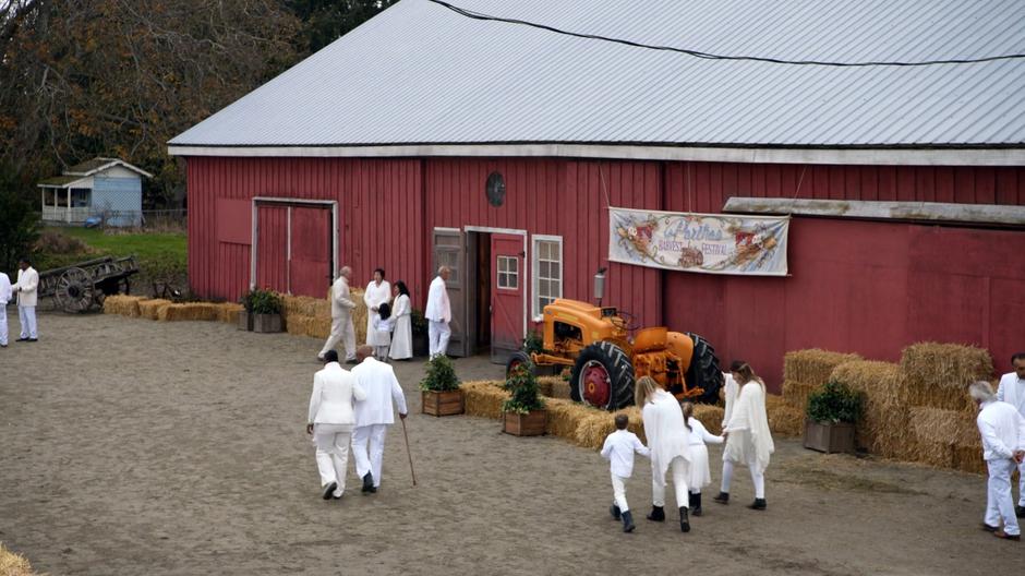 Townspeople dressed all in white walk into the barn for the memorial.