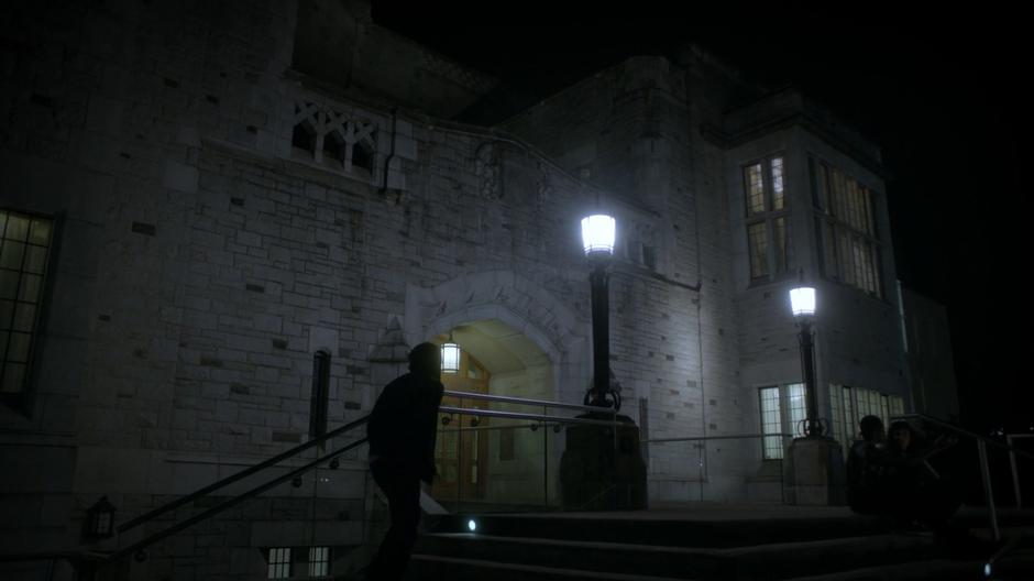 Students walk around outside the building at night.