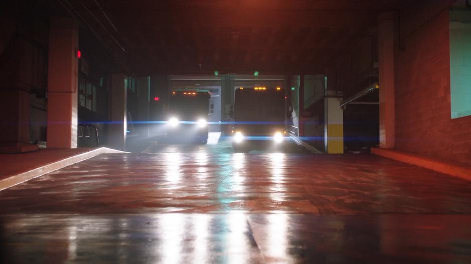 Two vans drive down into the parking garage.