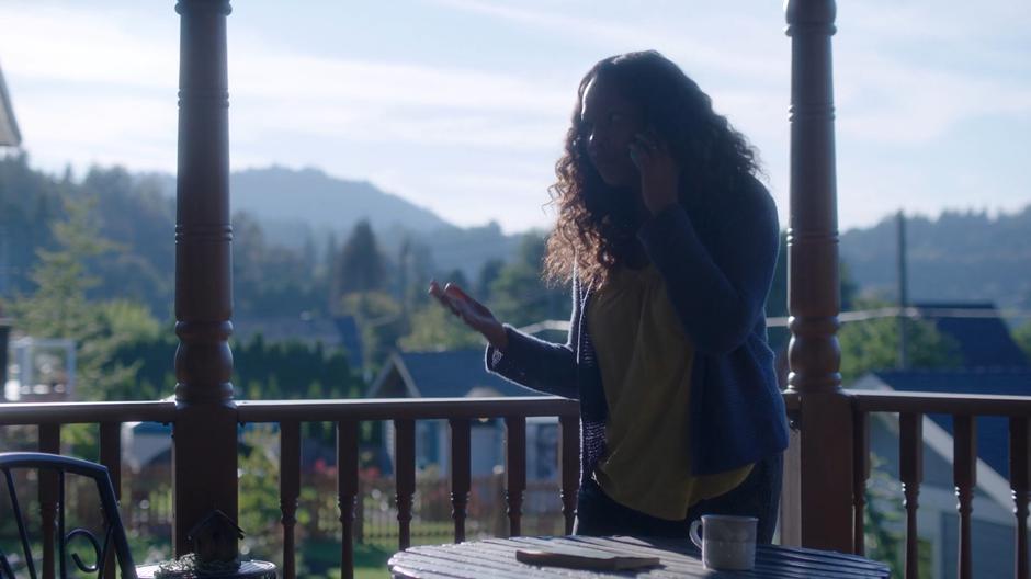 Susan talks to Maddie on the phone while standing on the back porch.