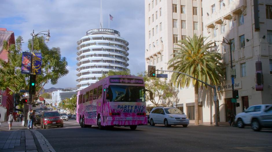 The party bus drives through the intersection during the day.