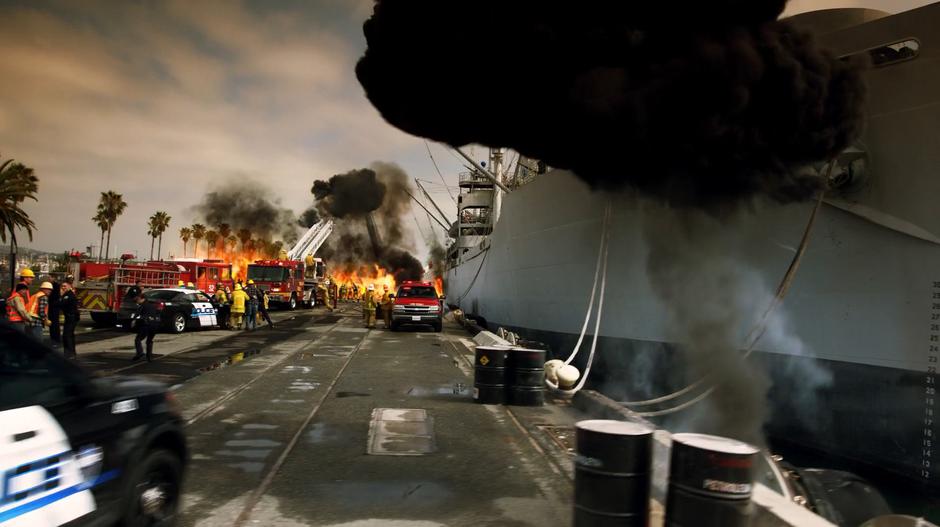 Firefighters try to put out a fire on the shore next to an oil tanker.