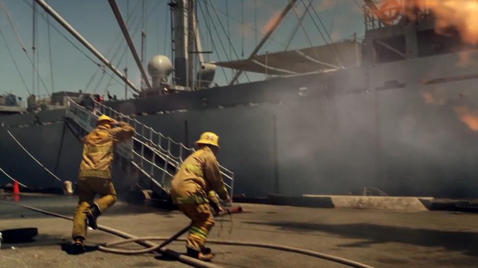 Two firefighters jump back as the fire flames up.