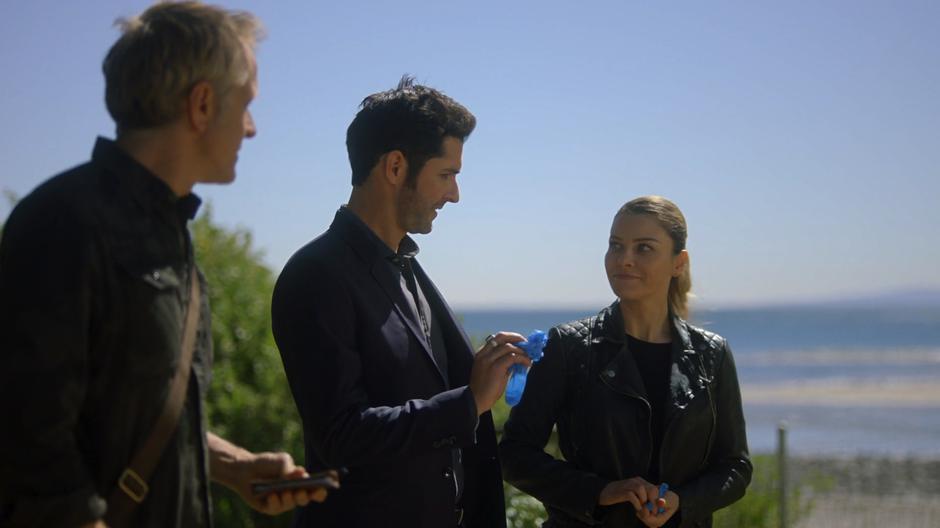 Reese watches as Chloe gives Lucifer a pair of gloves.