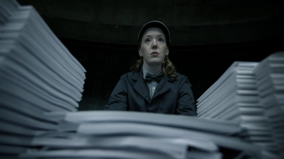 One of the workers pushes a cart covered in newly typed pages through the room.