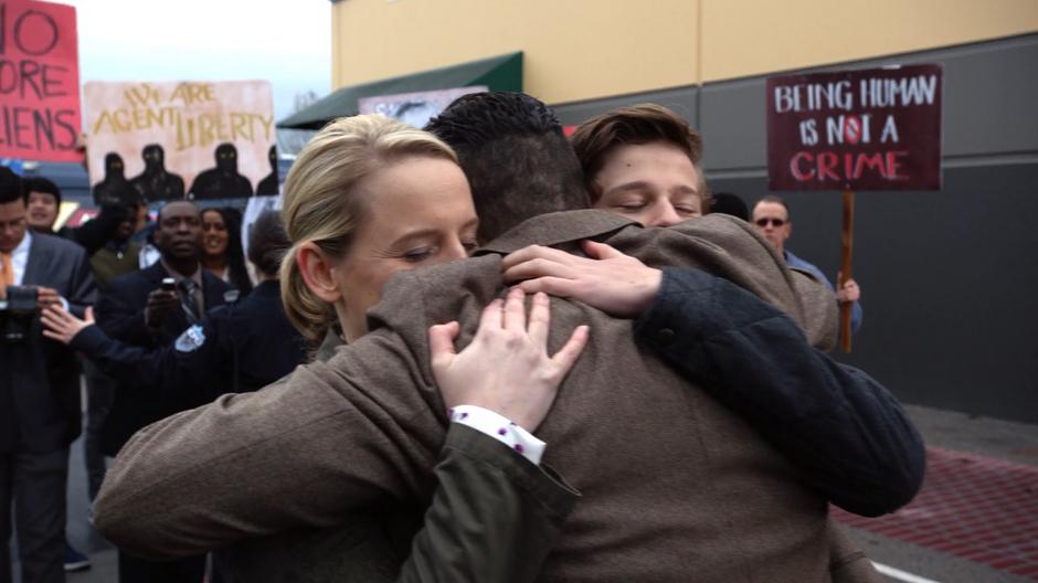 Lydia and George Lockwood hug Ben in front of a crowd of supporters.