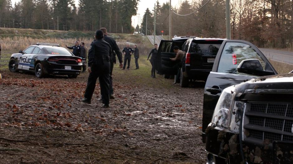 Alex and Colonel Haley both exit different vehicles while police officers surround the crash site.