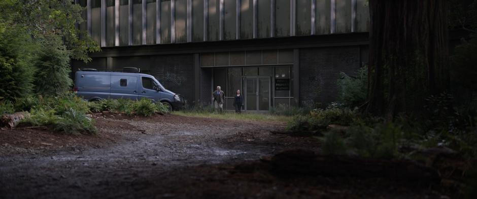 Hank and Hope exit their lab which is sitting in a clearing in the woods.