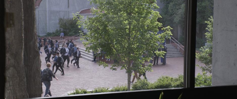 Agent Woo runs at the front of a group of FBI agents through the plaza outside.