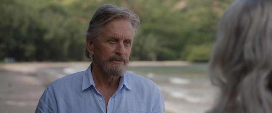 Hank looks at Janet as they stand on the beach.