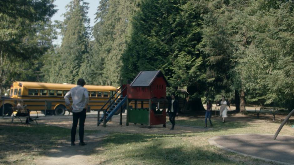 Alice sits off to the side on a bench while Quentin waits for the monster in Eliot's body, Julia, and Shoshana to approach.