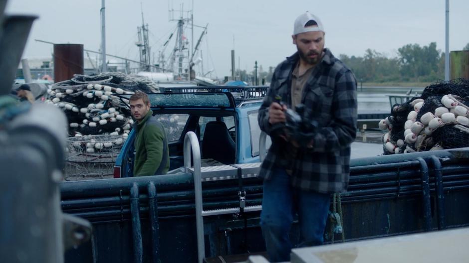 Ben looks at Xander as he is unloading his equipment onto Xander's boat.