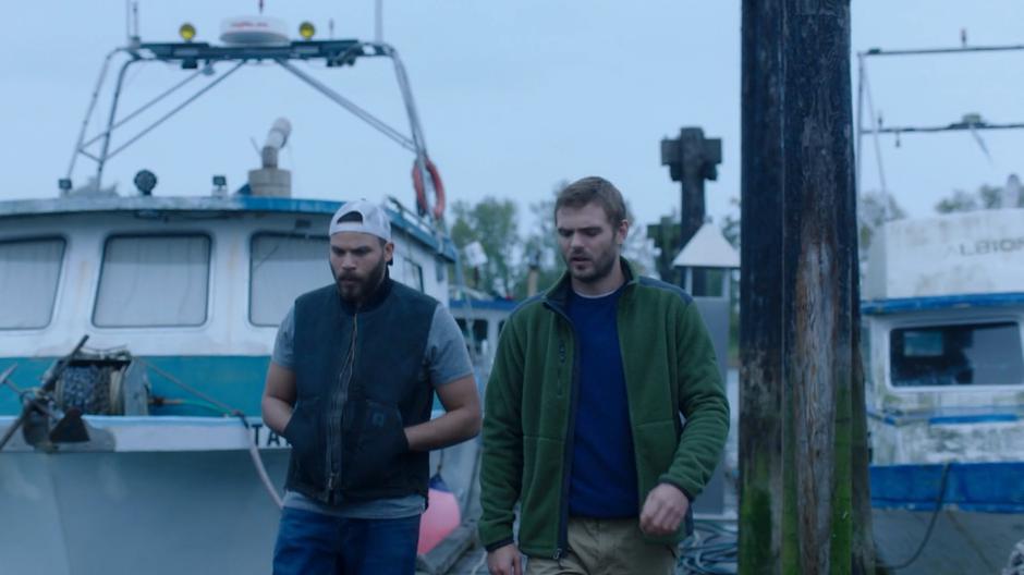 Xander and Ben walk down the dock past the boats.