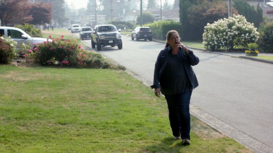 Shelia smokes a cigarette while walking back home.