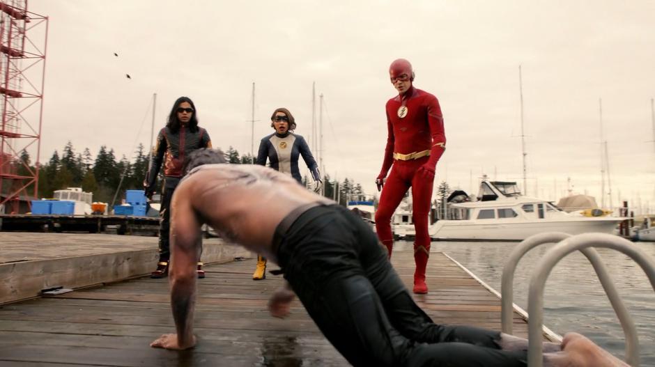 Cisco, Nora, and Barry watch as Shay Lamden climbs onto the dock after being transformed back from King Shark.