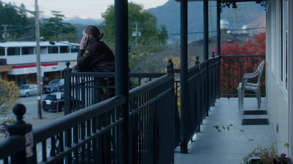 Deputy Staub leans against the second floor railing while talking to Dale on the phone.