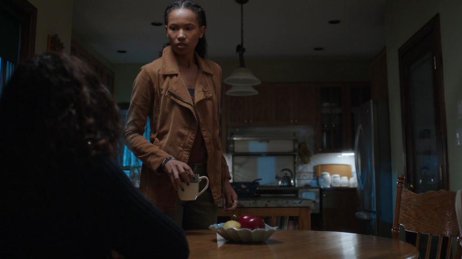 Maddie sets a mug of coffee on the dining room table in front of her mother.