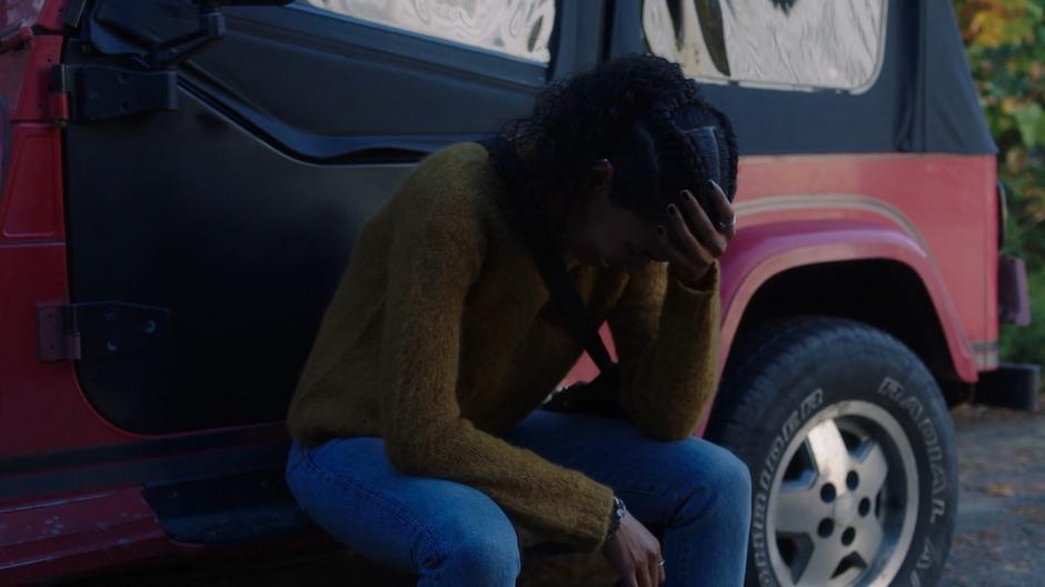 Maddie sits on the edge of her car crying.