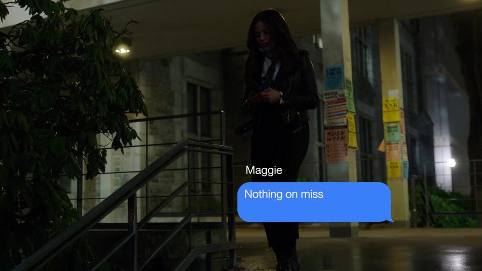 Mel texts her sisters on Maggie's phone while walking down the steps outside the building.