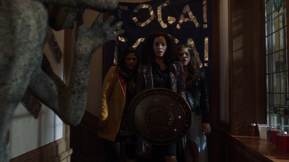 Macy lowers the shield from in front of Mel and Maggie and looks at everyone in the hallway frozen into stone.