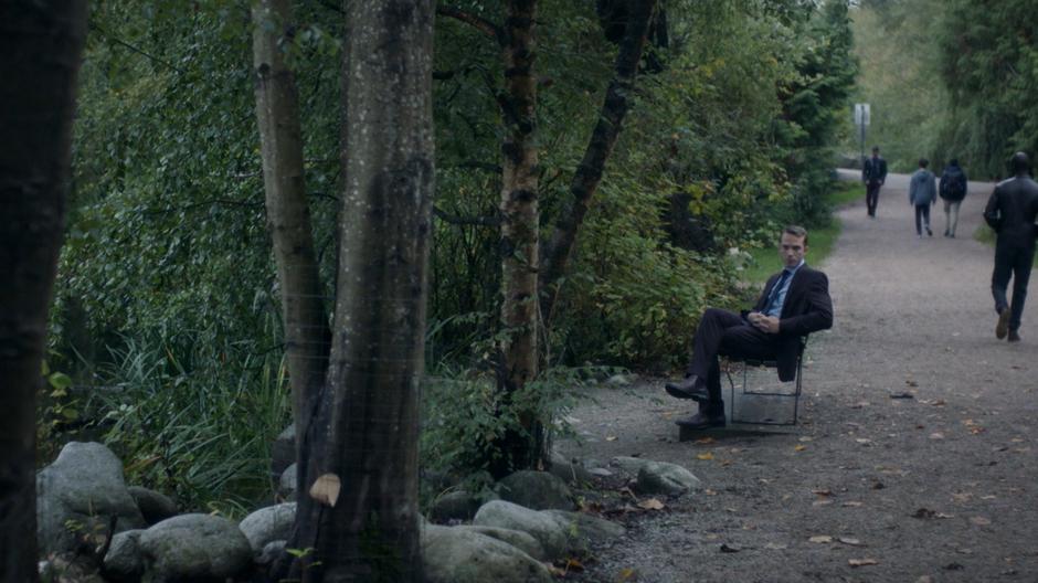 Pete watches the meeting while sitting on a bench down the path.