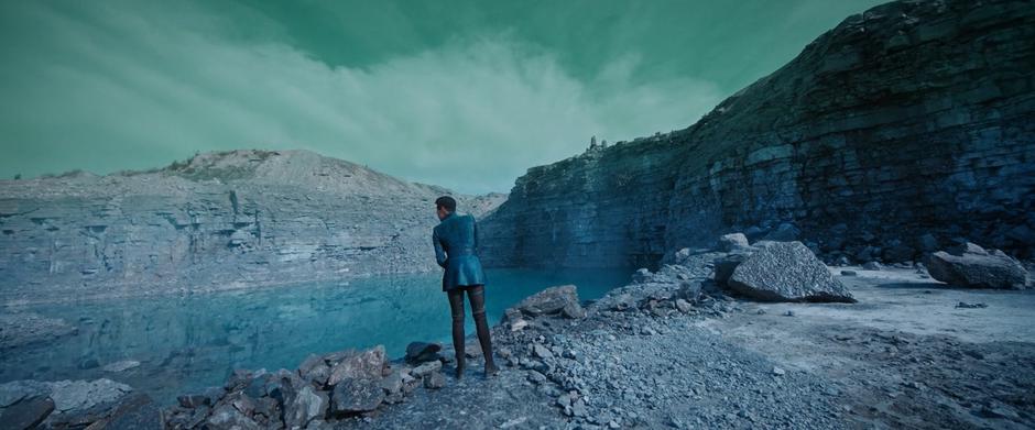 Michael stands at the edge of the lake in the crater and looks around.