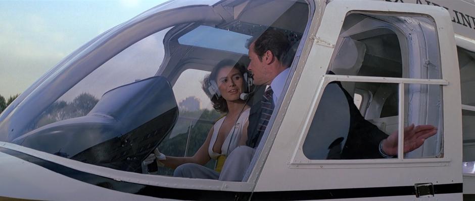 Corinne Dufour greets Bond from the pilot's seat as he closes the door to the helicopter.