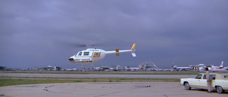 The driver watches as the helicopter lifts off from the pad.