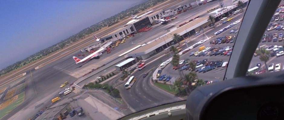 The helicopter flies over the airport terminal.