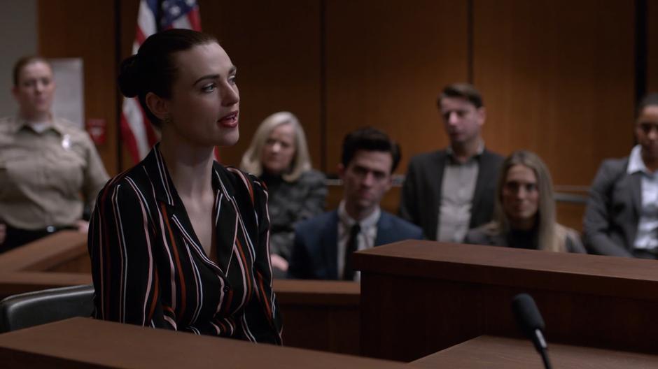 Lena testifies against Lex while the jury watches behind her.