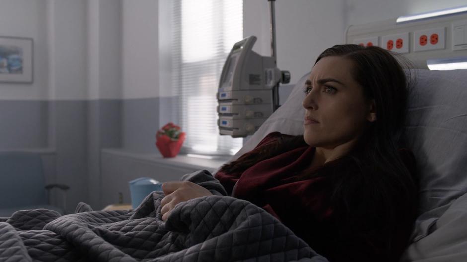 Lena lies in her hospital bed watching a news report on Lex's escape.