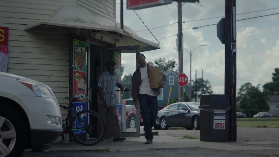 Otis walks out of the store and says goodbye to his friend.