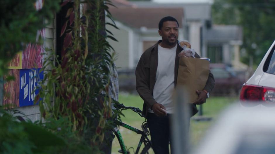 Otis Johnson walks down the sidewalk with an armful of groceries.