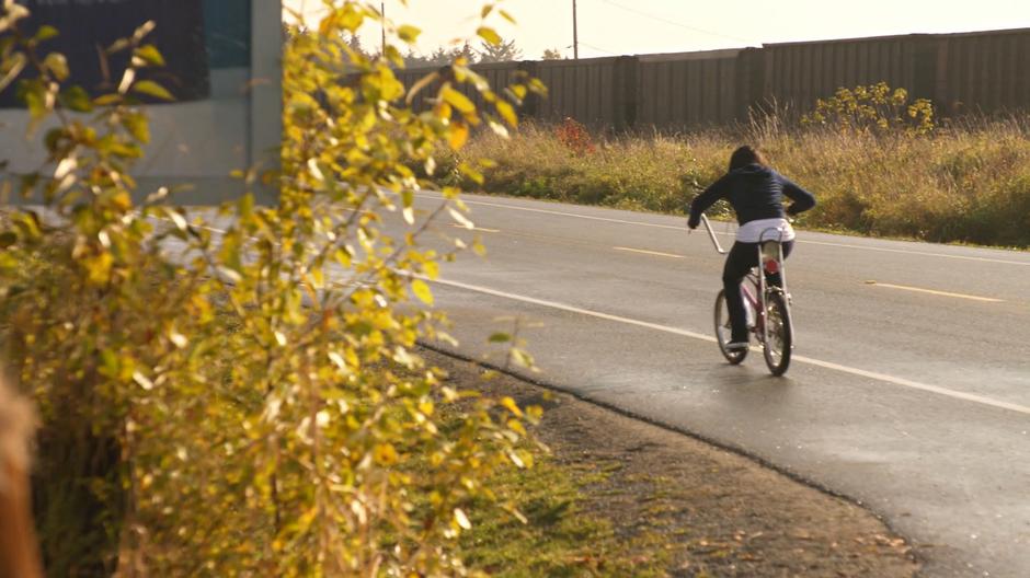 Mona rides off on the bike from the back of the RV.