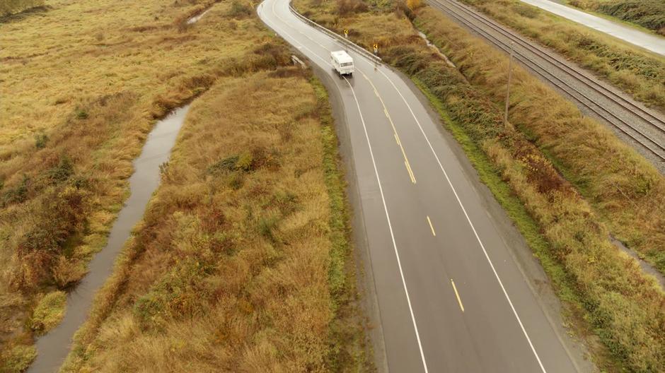 The RV drives around a bend while heading down a country highway.