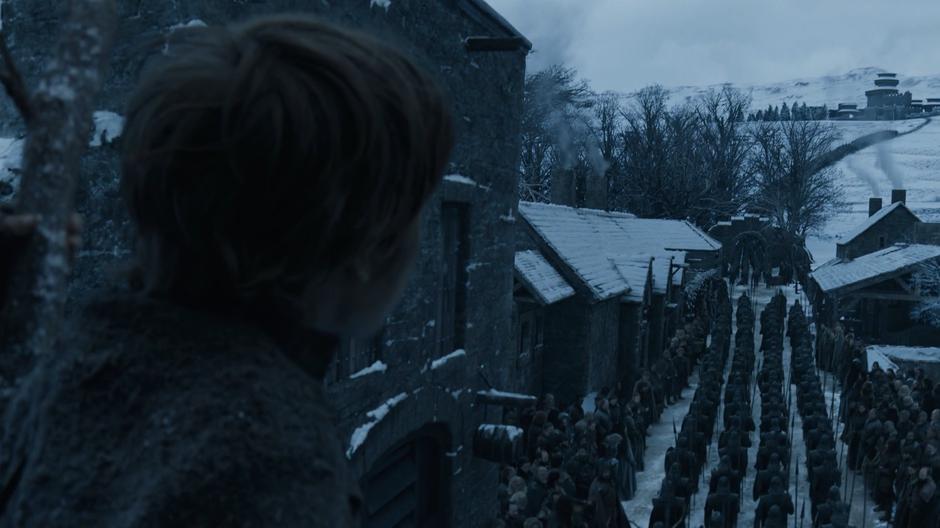 A small child watches as the soldiers march through the center of the village while he is perched up a tree.