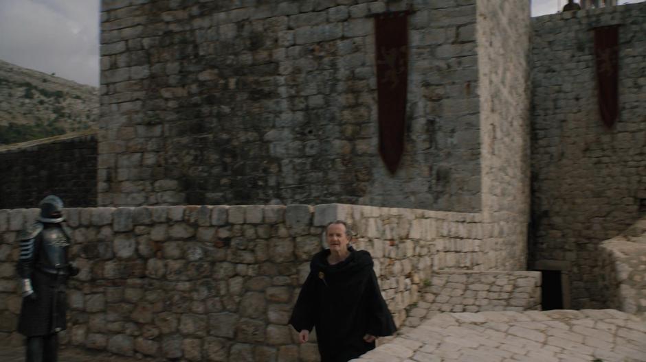 Qyburn walks along the wall towards Cersei.