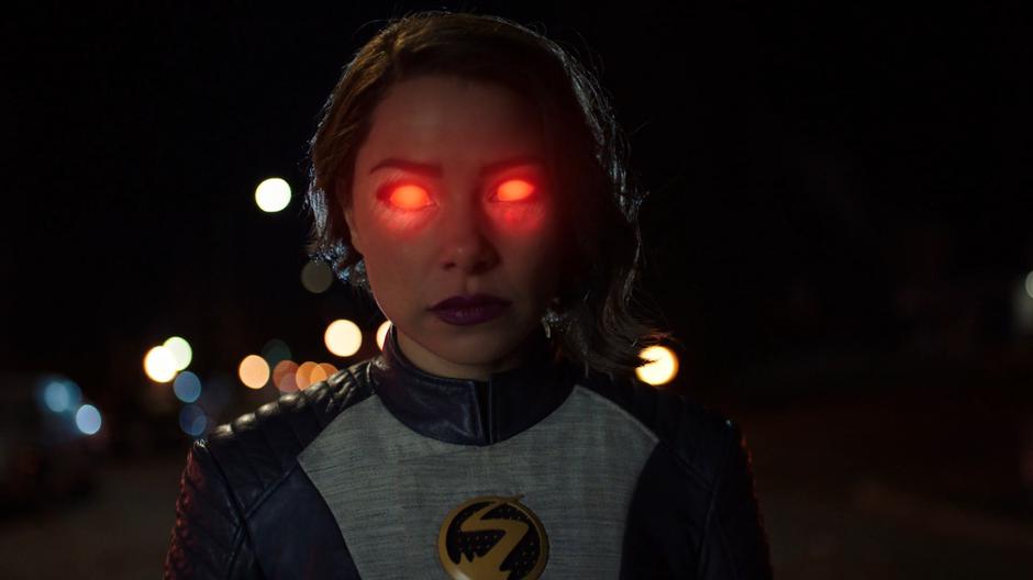 Nora stands in the street with her eyes glowing red.