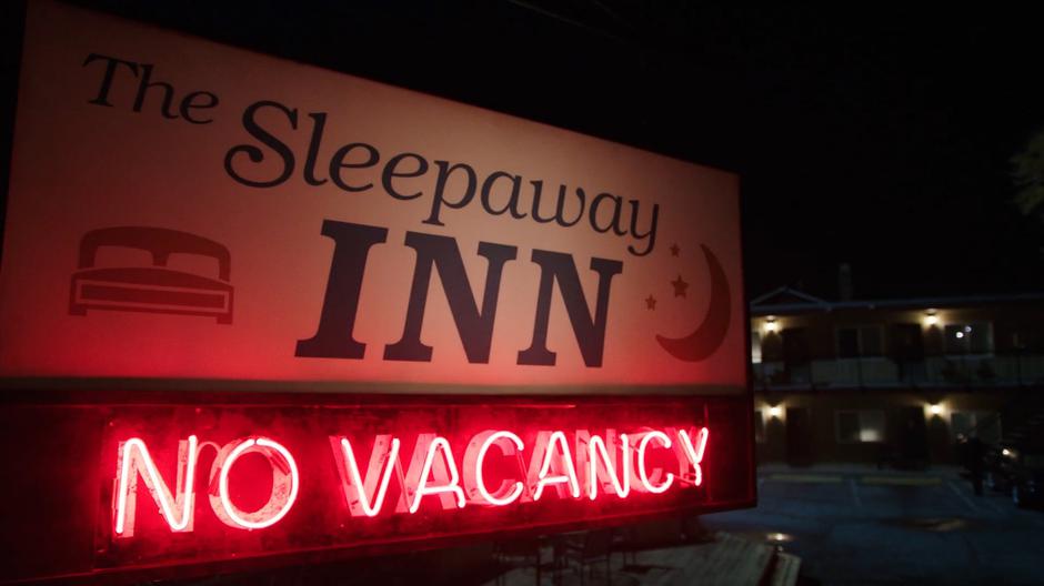 The *No Vacancy* sign glows below a sign advertising The Sleepaway Inn.
